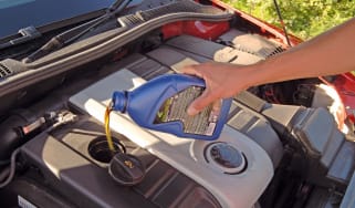 Person topping up engine oil